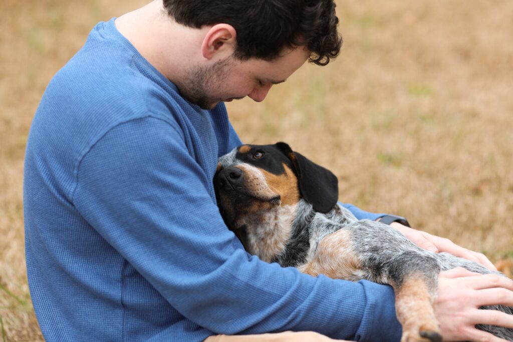 a man sits outside with a beagle type dog in his lap